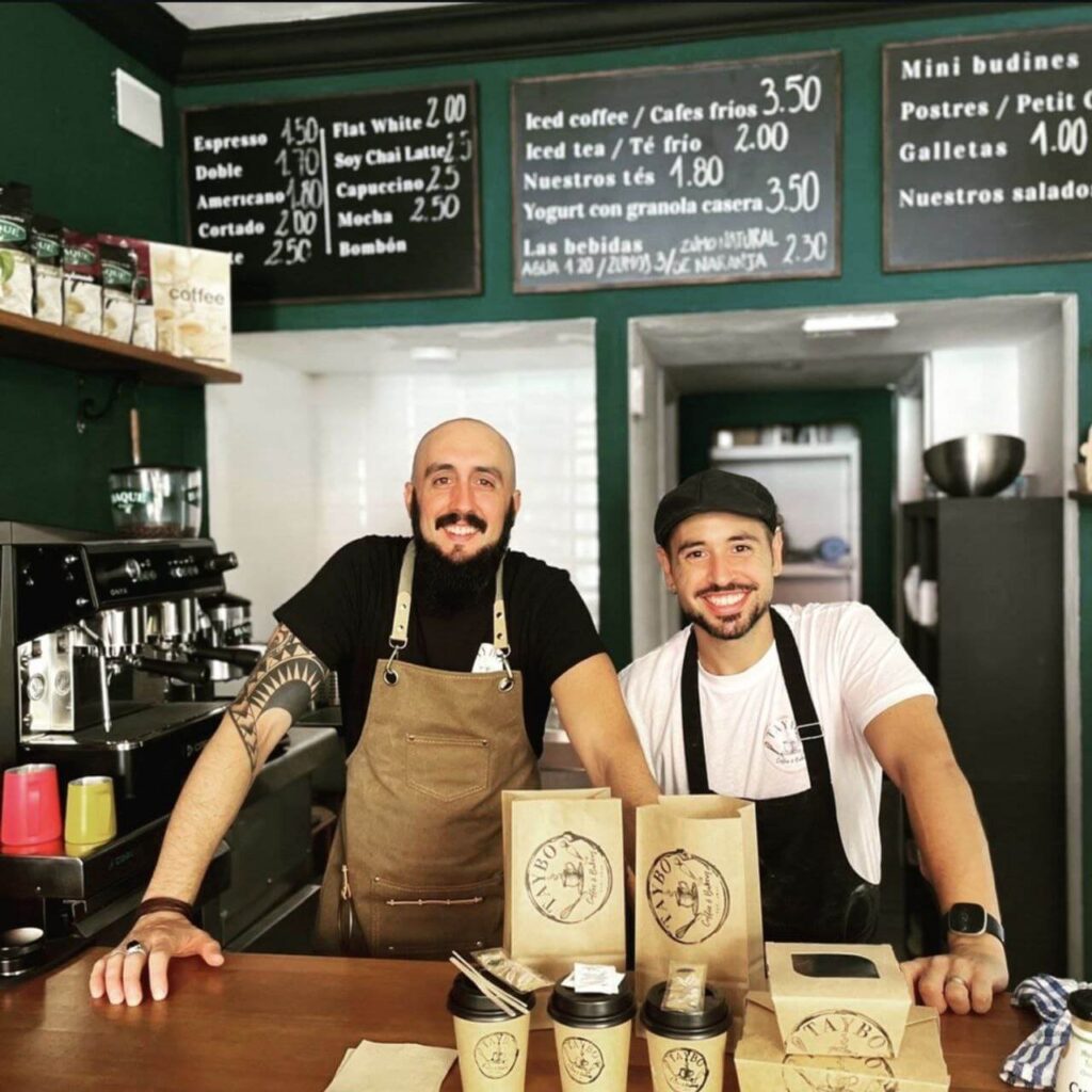 Se ven a los dos dueños de Taybo Bagels & Coffee. Gonzalo (a la izquierda) y Dani (a la derecha) son los emprendedores de esta cafetería de café de especialidad en el corazón de Málaga y se les ve posando, detrás de la barra con los brazos apoyados sobre esta, sonrientes y orgullosos en su primer local del que ya se han movido. Ahora tienen un segundo más grande en la misma Calle Victoria.